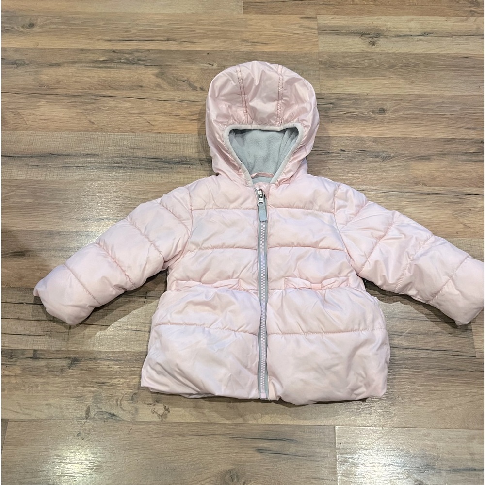 Baby pink puffy coat with bow accent pockets.